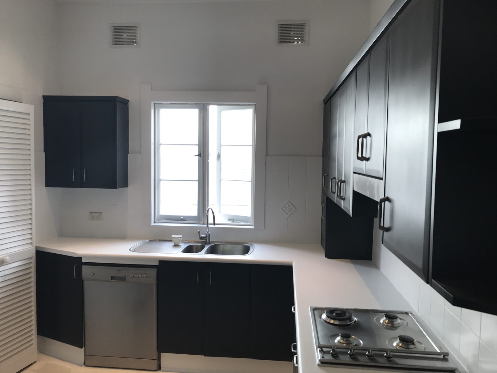 A kitchen after its cabinets were repainted in a deep charcoal finish