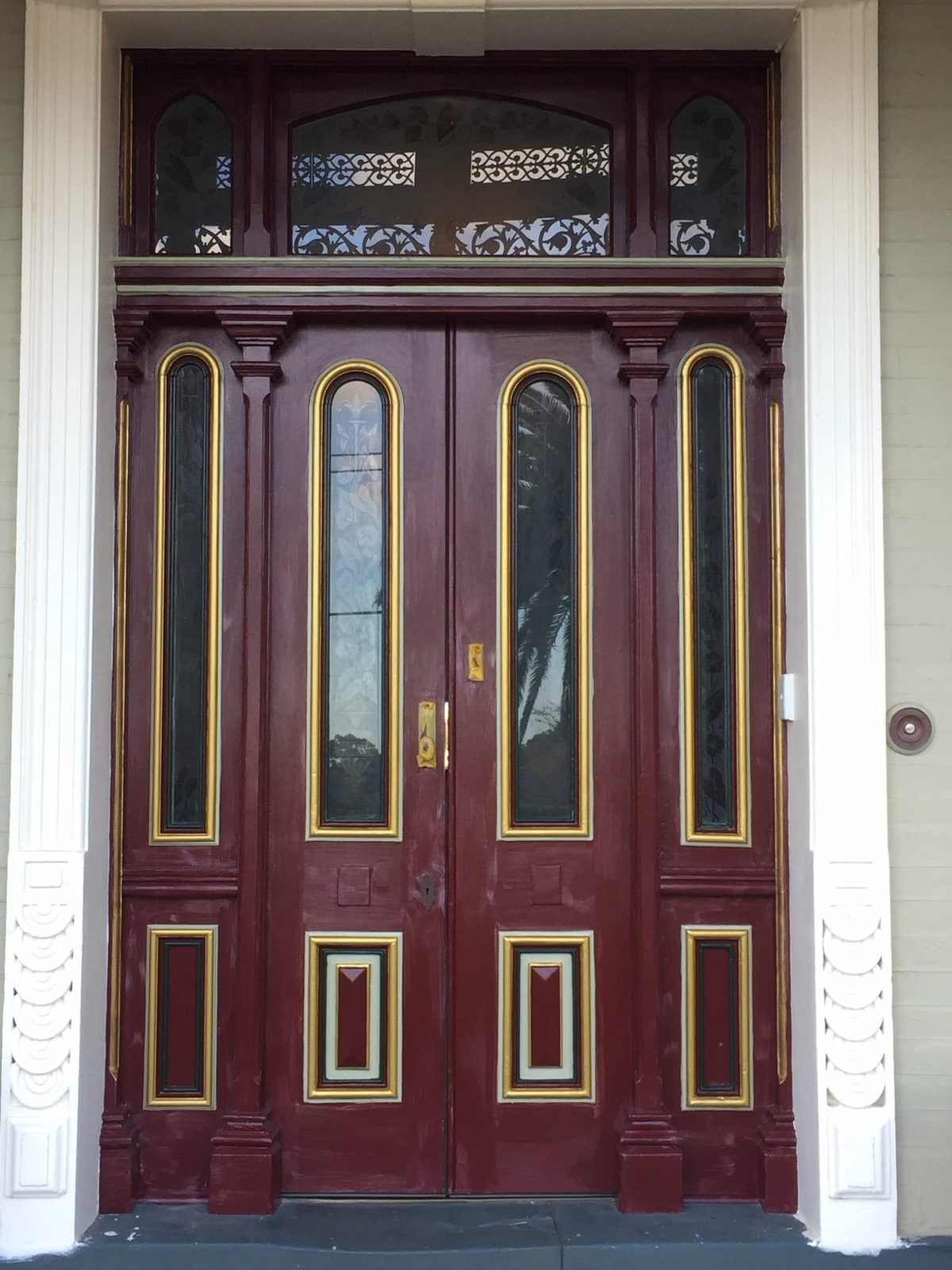 A heritage front door fully restored in deep burgundy with gilt detail