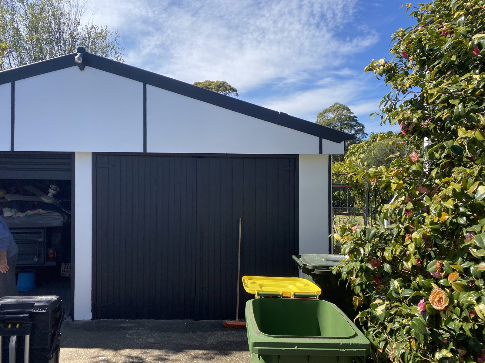 A timber garage repainted crisp white with charcoal doors and trim