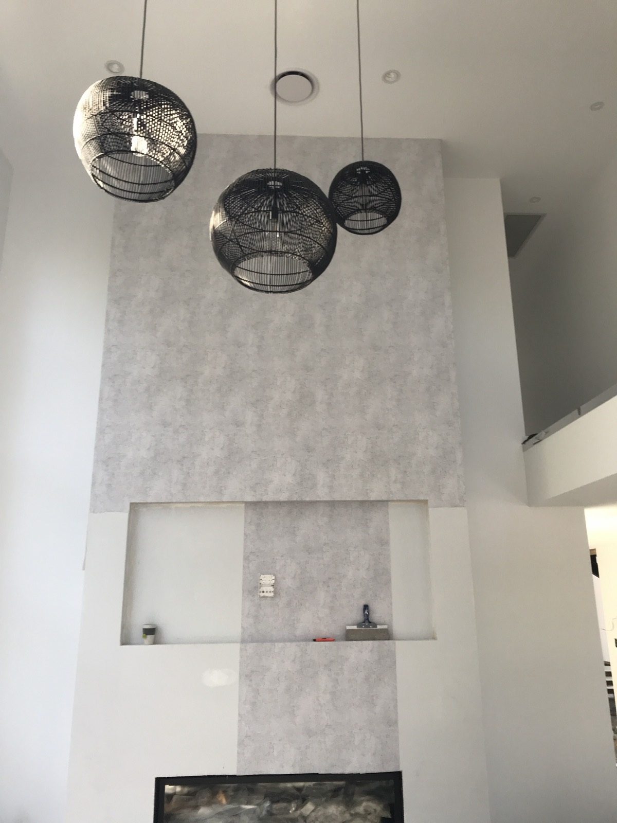 A freshly painted double-height feature wall with pendant lights