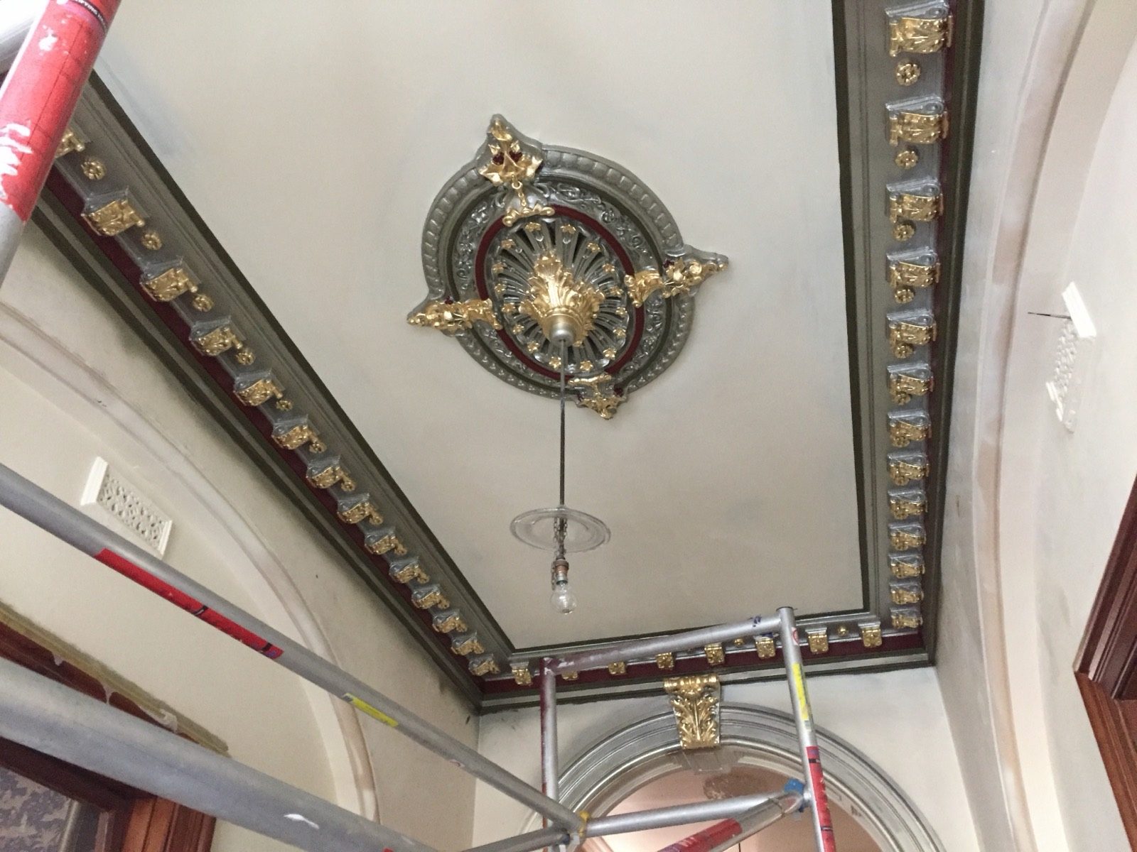 A restored ornate ceiling rose with gilded and silvered detailing